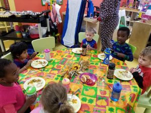 Toddlers sitting around a table eating dinner