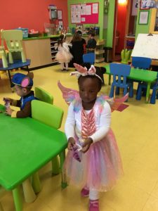 Toddler in a pink fairy costume with a halloween bag of candy