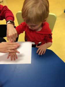 Toddler about to press hand with red paint on to paper