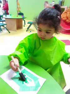 Toddler filling in an outline with green paint