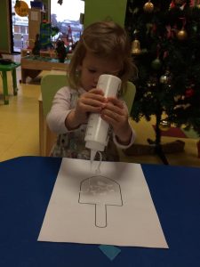 Toddler working on a dreidel art project using white paint