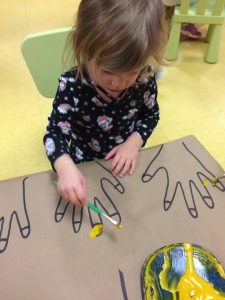 Toddler painting a hand drawing's nails