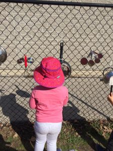 Toddlers wearing pink playing with kitchen equipment on a chain fence