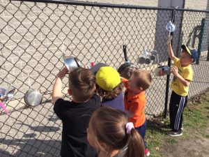 Kids playing with kitchen equipment on a chain fence