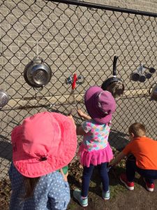 Toddlers playing and having fun with kitchen equipment on a chain fence