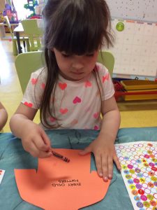 Toddler about to draw on an orange shirt