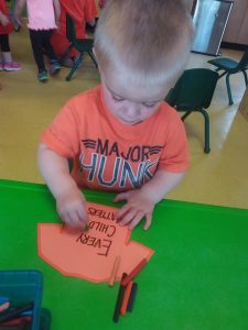 Toddler putting their hands on an orange shirt