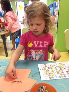 Toddler placing stickers on an orange shirt