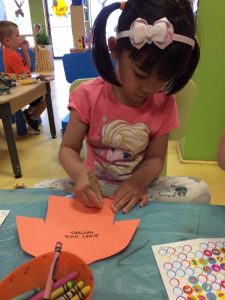 Toddler placing a few stickers on an orange shirt