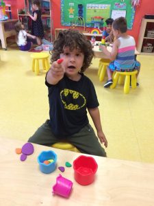 Toddler wearing a batman shirt showing off his red plasticine