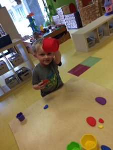 Toddler waving to the camera with red plasticine