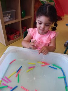 Kid playing with string and colourful pieces 