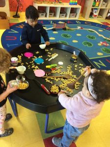 Toddlers having fun with uncooked pasta