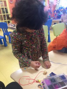 Little kid making a necklace during an activity