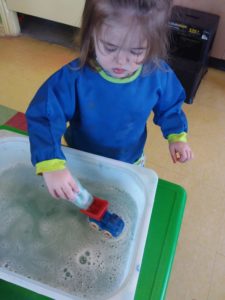 Kid in the middle of playing with a toy can & washing it