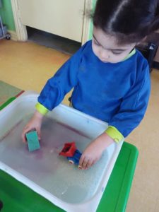 Kid cleaning a toy truck in a pool of water