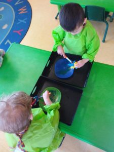 Two kids painting toy cars and trucks