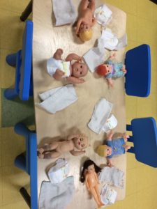 Baby dolls on a table with diapers and towels