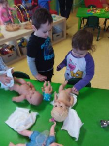 Kids playing with baby dolls on a green table