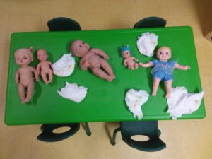 Baby dolls spread around on a green table