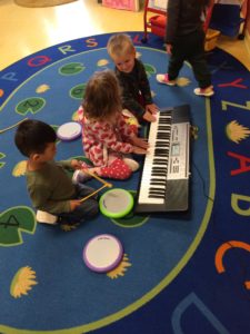 Kids playing on the piano on a rug