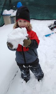 Toddler holding up a big chunk of snow