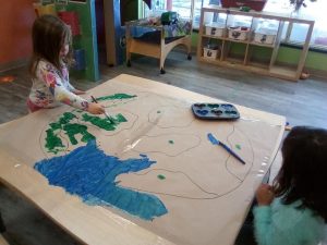 Toddler's drawing a picture of the globe and colouring it in with paint