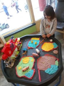Toddler playing with a farm toy set on a table