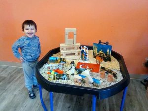 Toddler smiling with a bunch of toys on a table