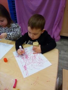 Toddler drawing with red crayon