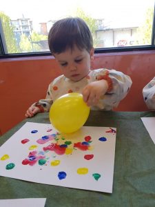 Toddler having fun painting with a balloon