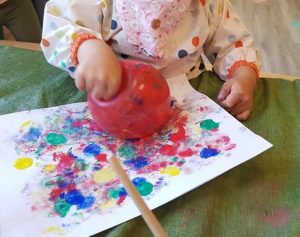Toddler smudging a balloon all over paint