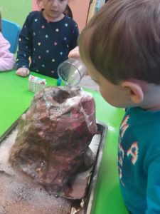 Kid pouring liquid into a volcano