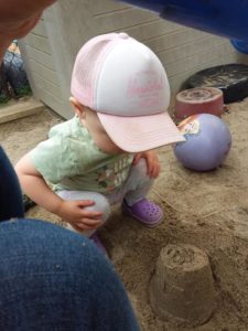 Toddler looking at a mini sand castle