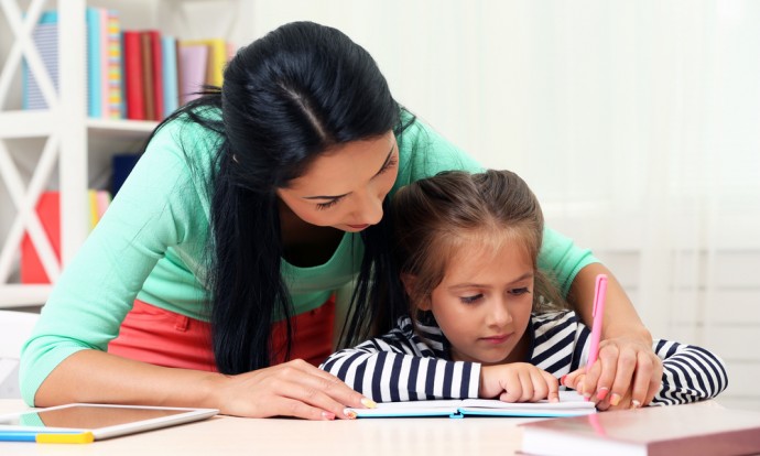 A woman helps a young girl with her homework