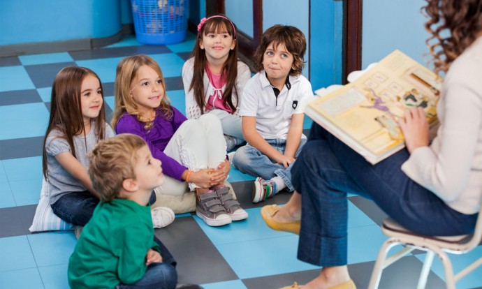 A group of children are read to by a daycare worker