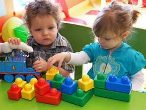 Two young children play with building blocks