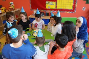 Children sit around a table with party hats on