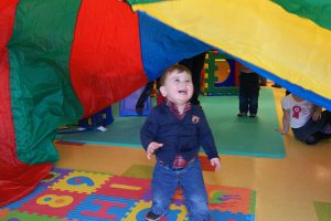 A child smiles from under a parachute