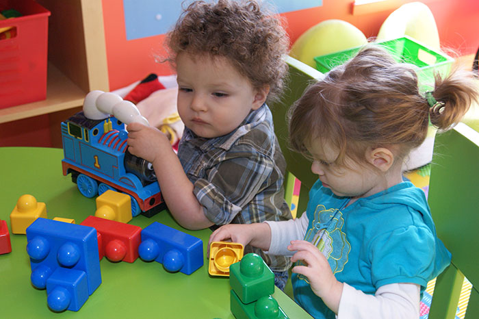 Two toddlers play with blocks